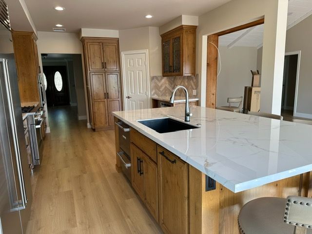 Bright kitchen with wood cabinets, large island, sink, and light hardwood floors