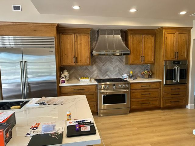 Modern kitchen with stainless steel appliances, wood cabinets, and a white island counter under recessed lights