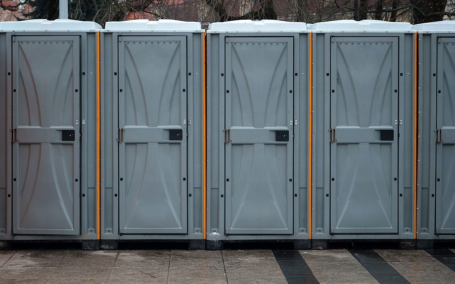 A row of portable toilets are lined up in a parking lot