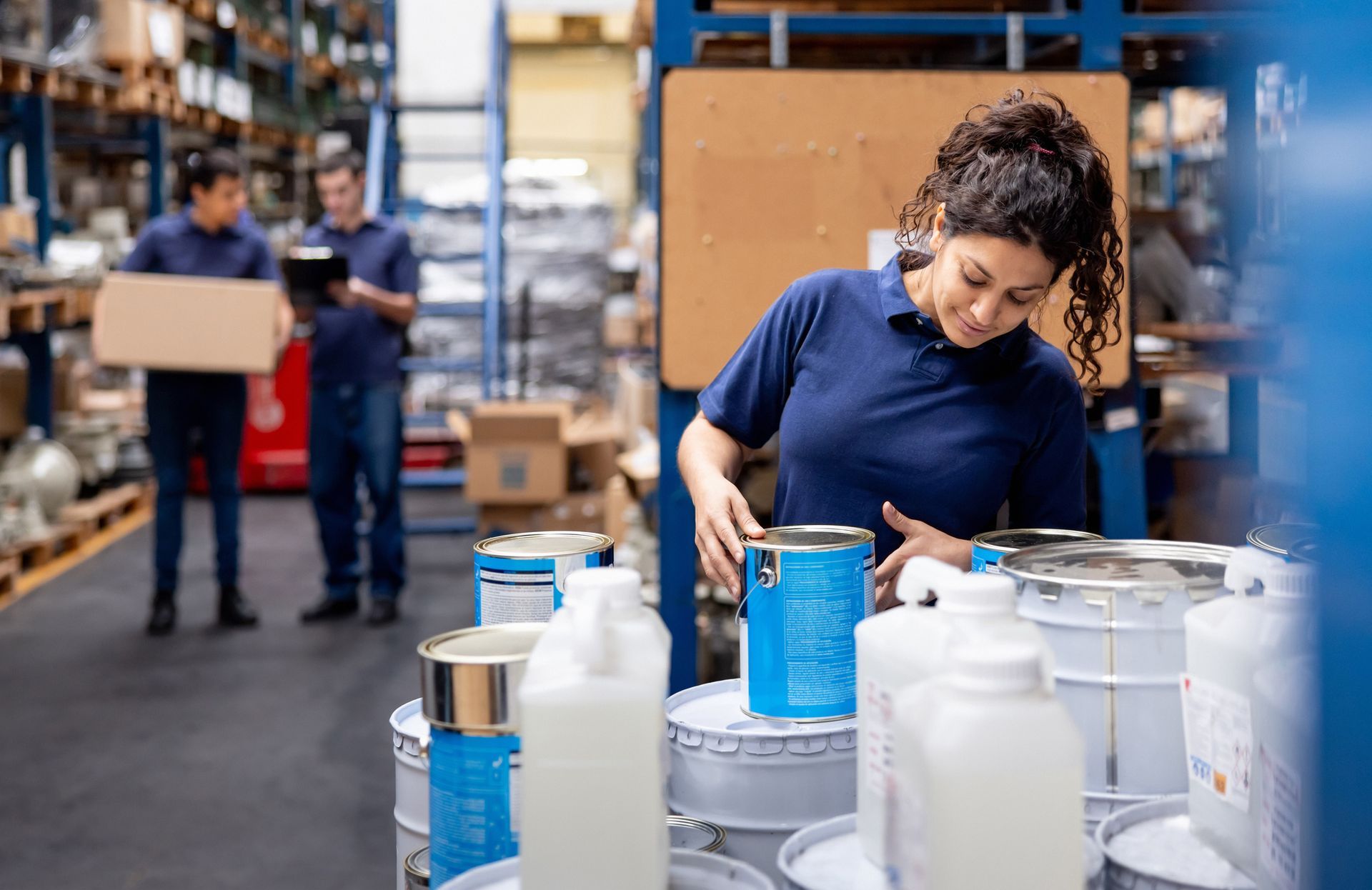 An employee is organizing cans of paint at a distribution warehouse. An employee is organizing cans of paint at a distribution warehouse.