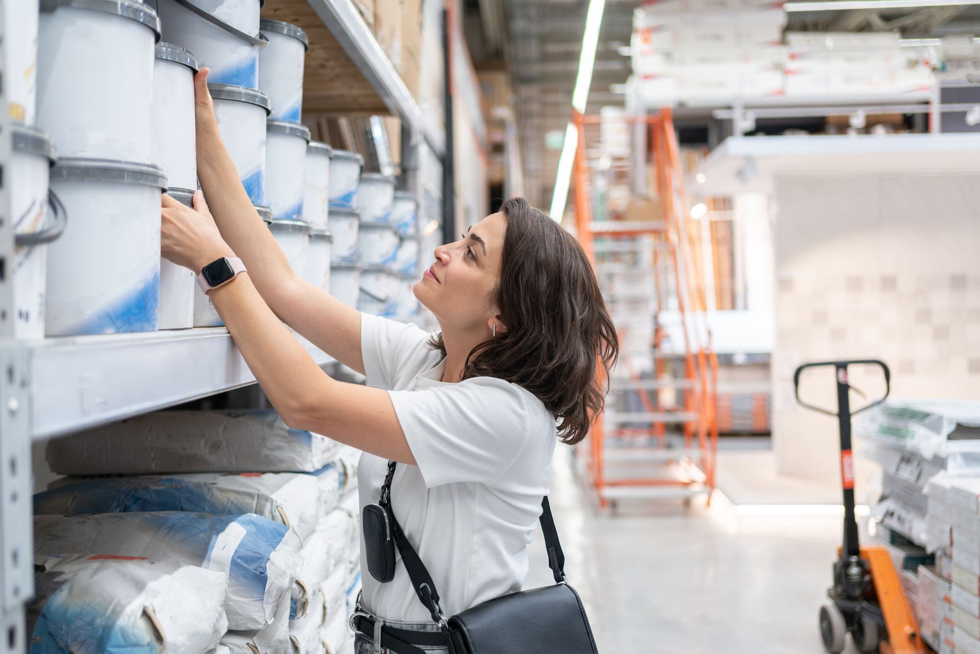 A woman choosing paint in a paint store, with colorful paint samples displayed around her.