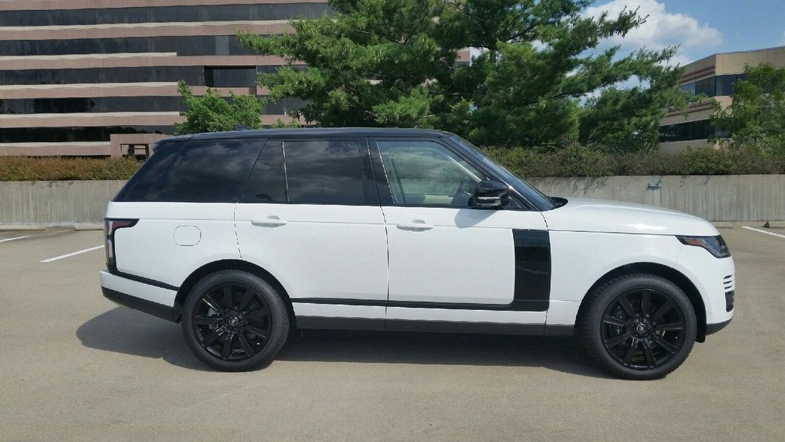 White Range Rover SUV with black accents and black wheels parked outside on a sunny day.