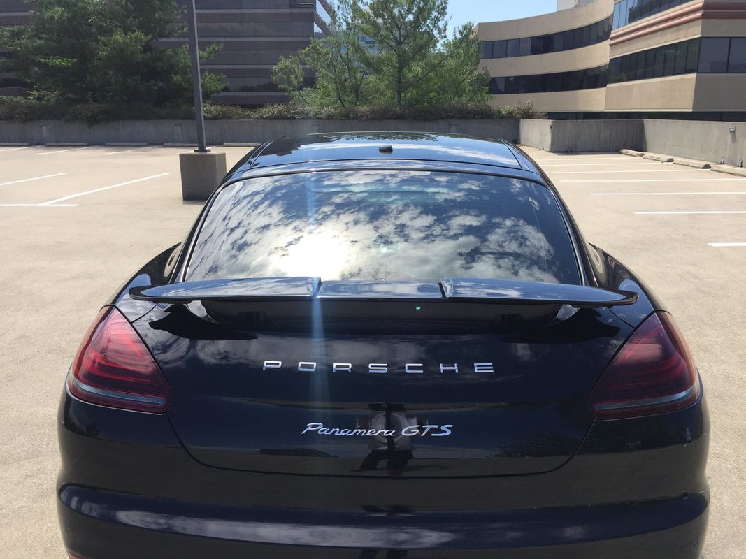 Black Porsche Panamera GTS parked outdoors with the word