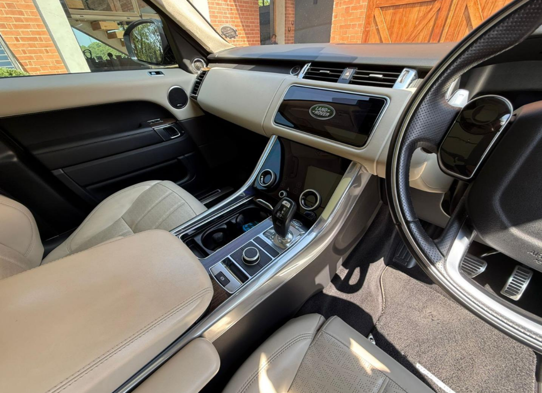 Tan and black interior of a Land Rover, with the steering wheel, console, and dashboard visible.