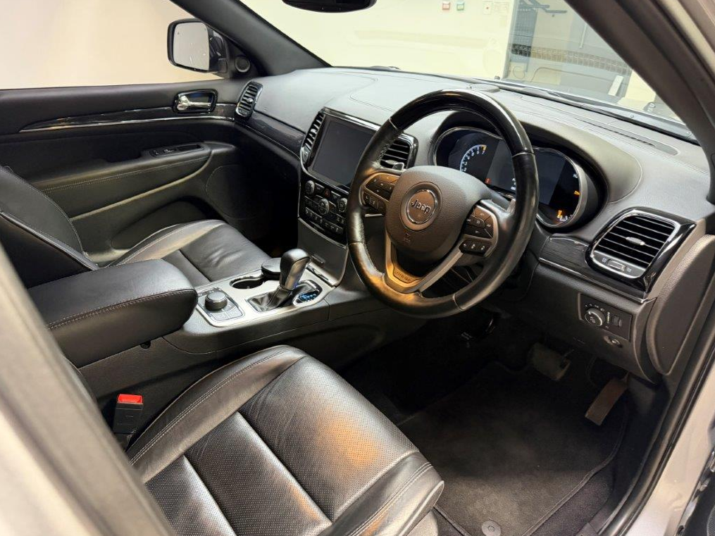 Interior of a black leather Jeep Grand Cherokee. Steering wheel, dashboard, and gear shift are visible.