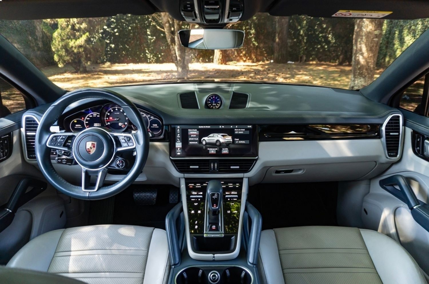 Interior view of a Porsche Cayenne SUV. Dashboard and light leather seats are visible.