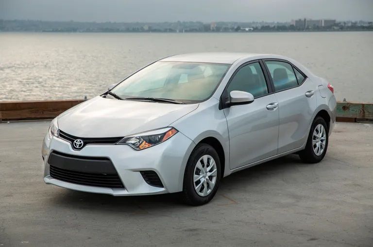 Silver Toyota Corolla sedan parked near a body of water.