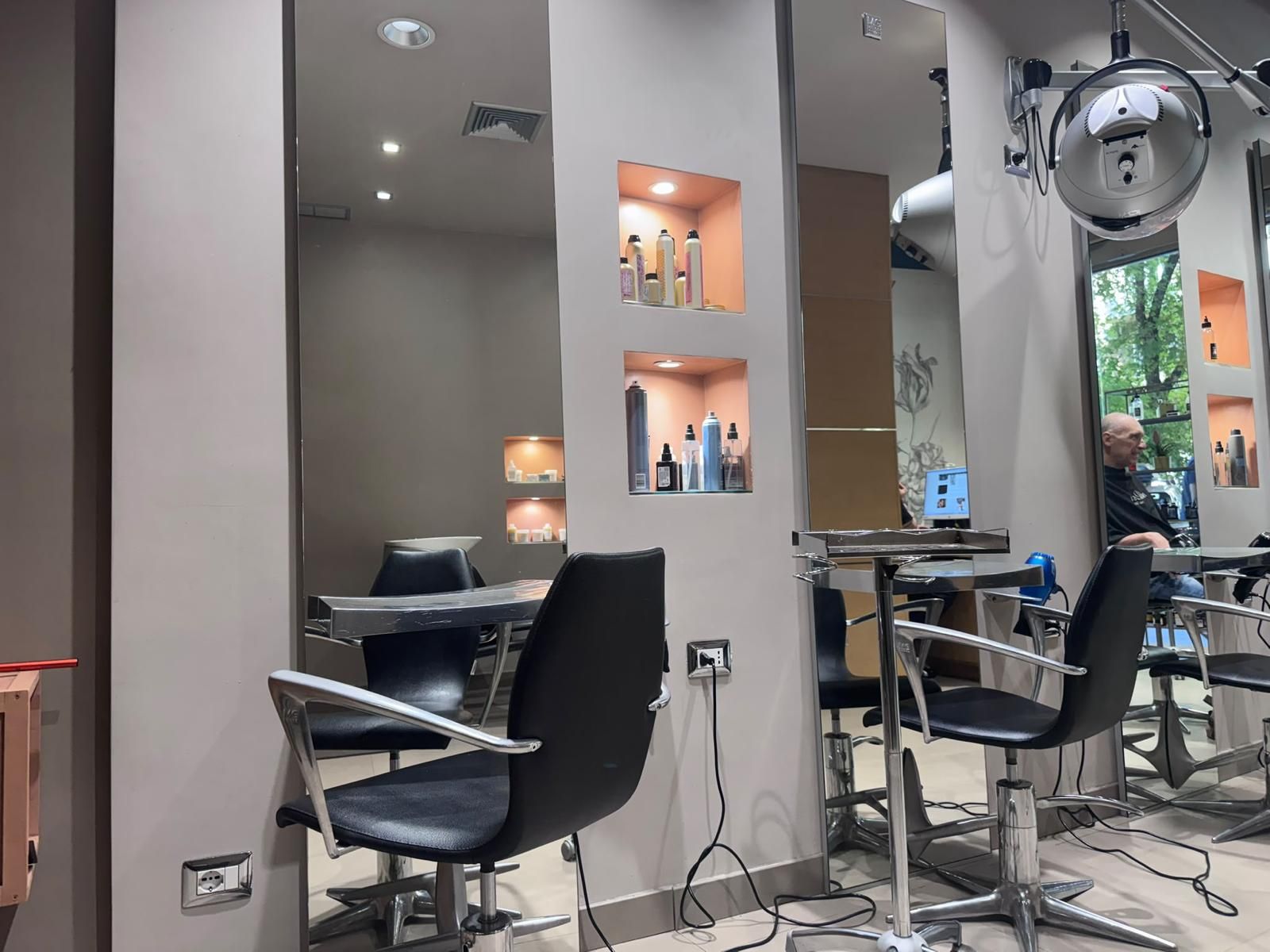 Interni di un salone moderno con poltrone da parrucchiere, specchi e nicchie a muro illuminate.