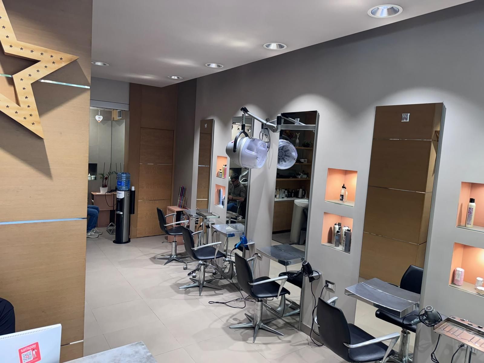 Salone da parrucchiere moderno con poltrone per lo styling, specchi, lavandini e illuminazione a incasso calda.
