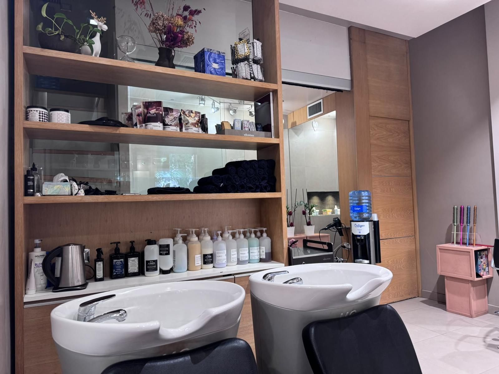 Bagno con due lavandini, mensole in legno, articoli da toeletta e specchio in un ambiente moderno simile a una spa.