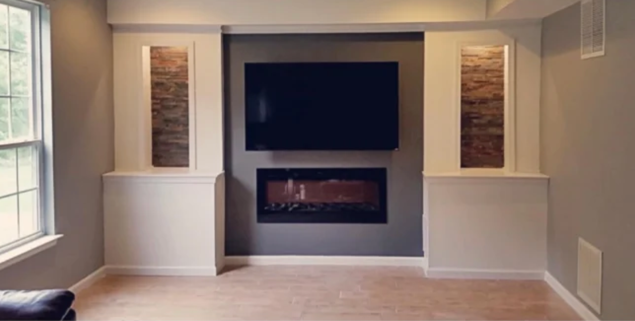 A living room with a fireplace and a flat screen tv on the wall.