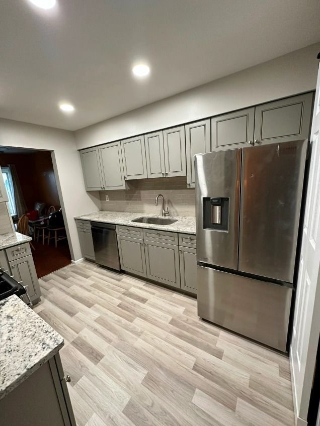 A kitchen with stainless steel appliances and gray cabinets.