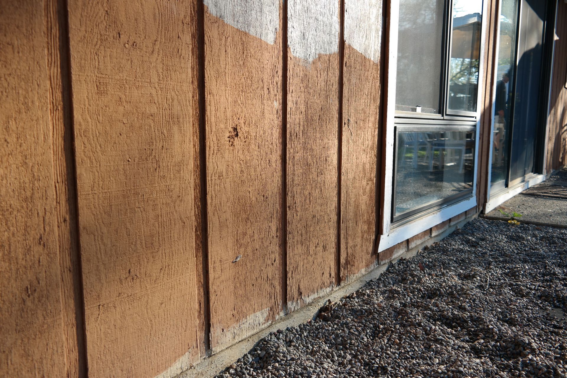 A brown building with a lot of windows and gravel in front of it.