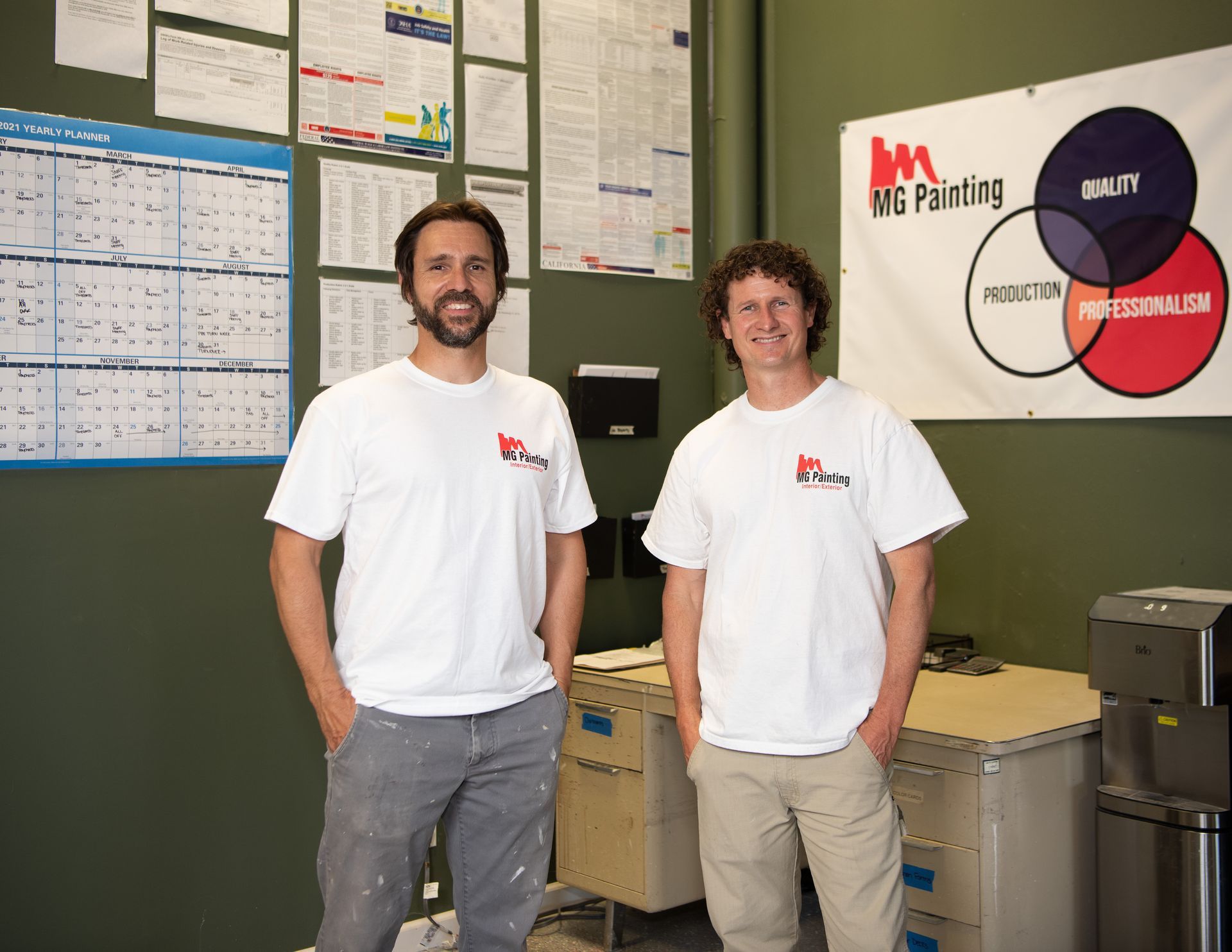 Two men standing in front of a ms painting sign