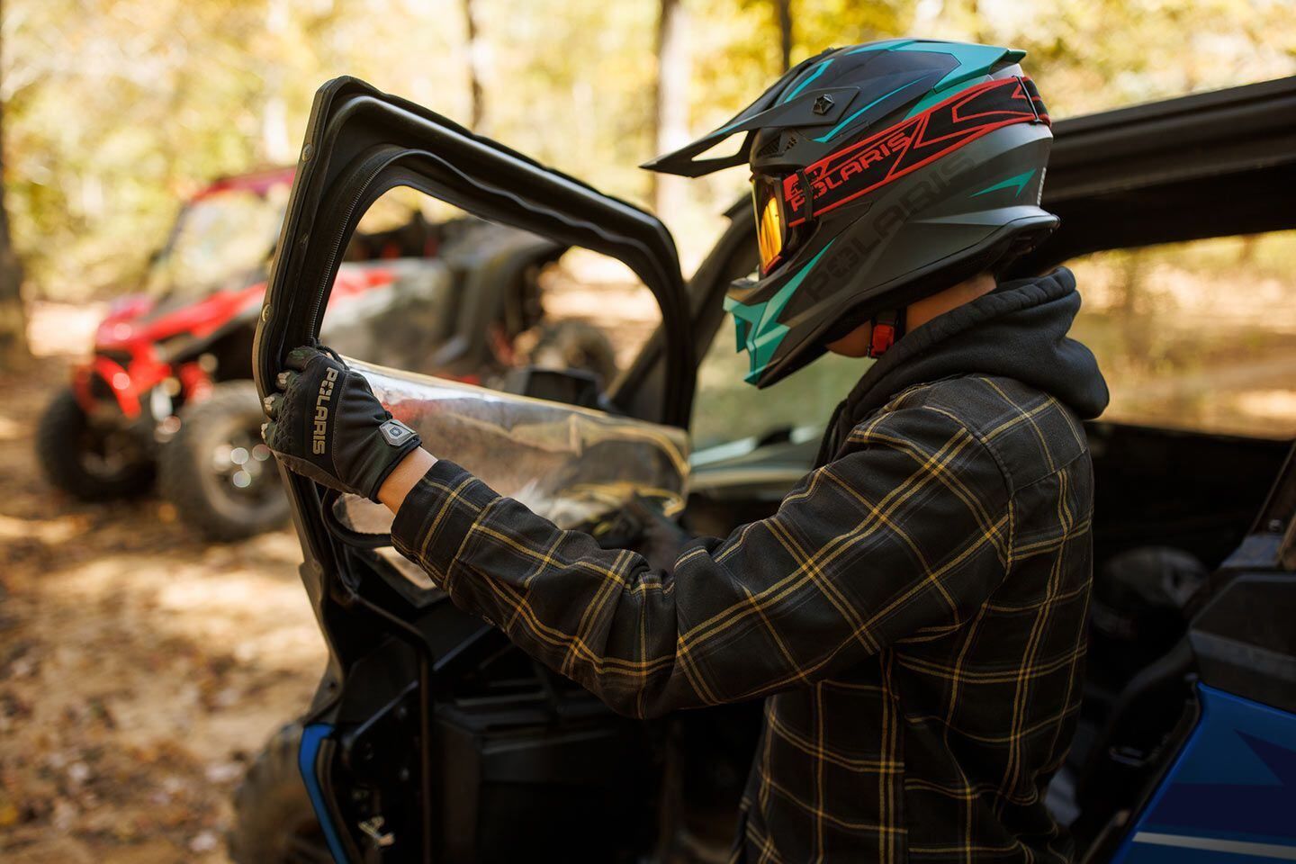 A man wearing a helmet is getting out of a atv.