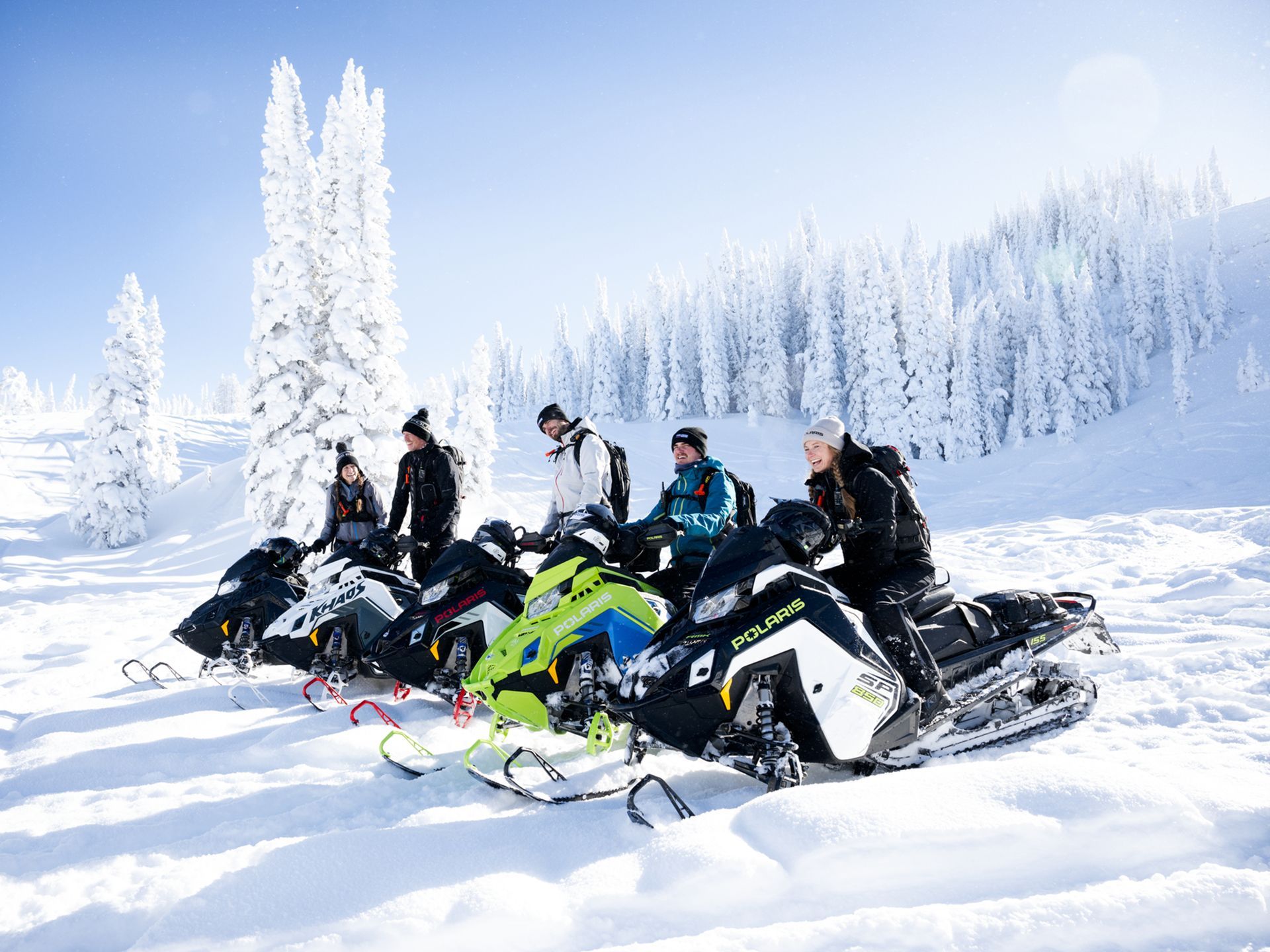 A group of people are sitting on snowmobiles in the snow.