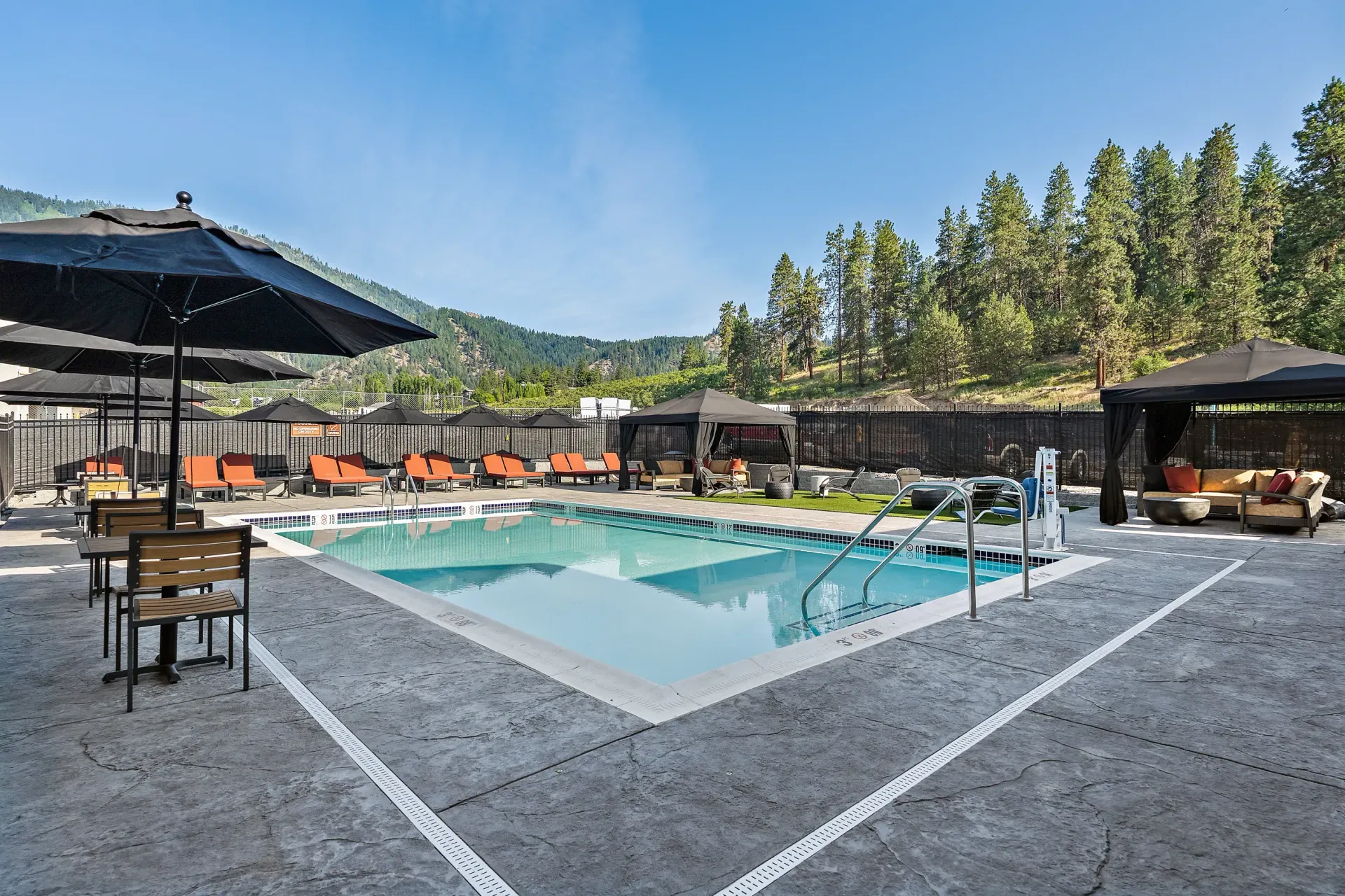 A large swimming pool with umbrellas and chairs around it.