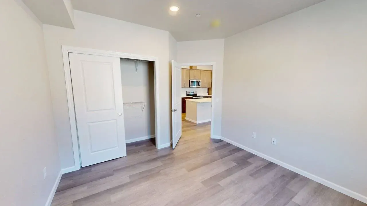 An empty room with hardwood floors and a closet.