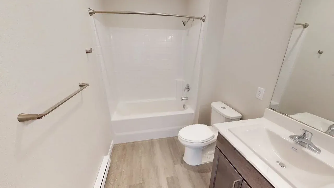 A bathroom with a toilet , sink , bathtub and mirror.
