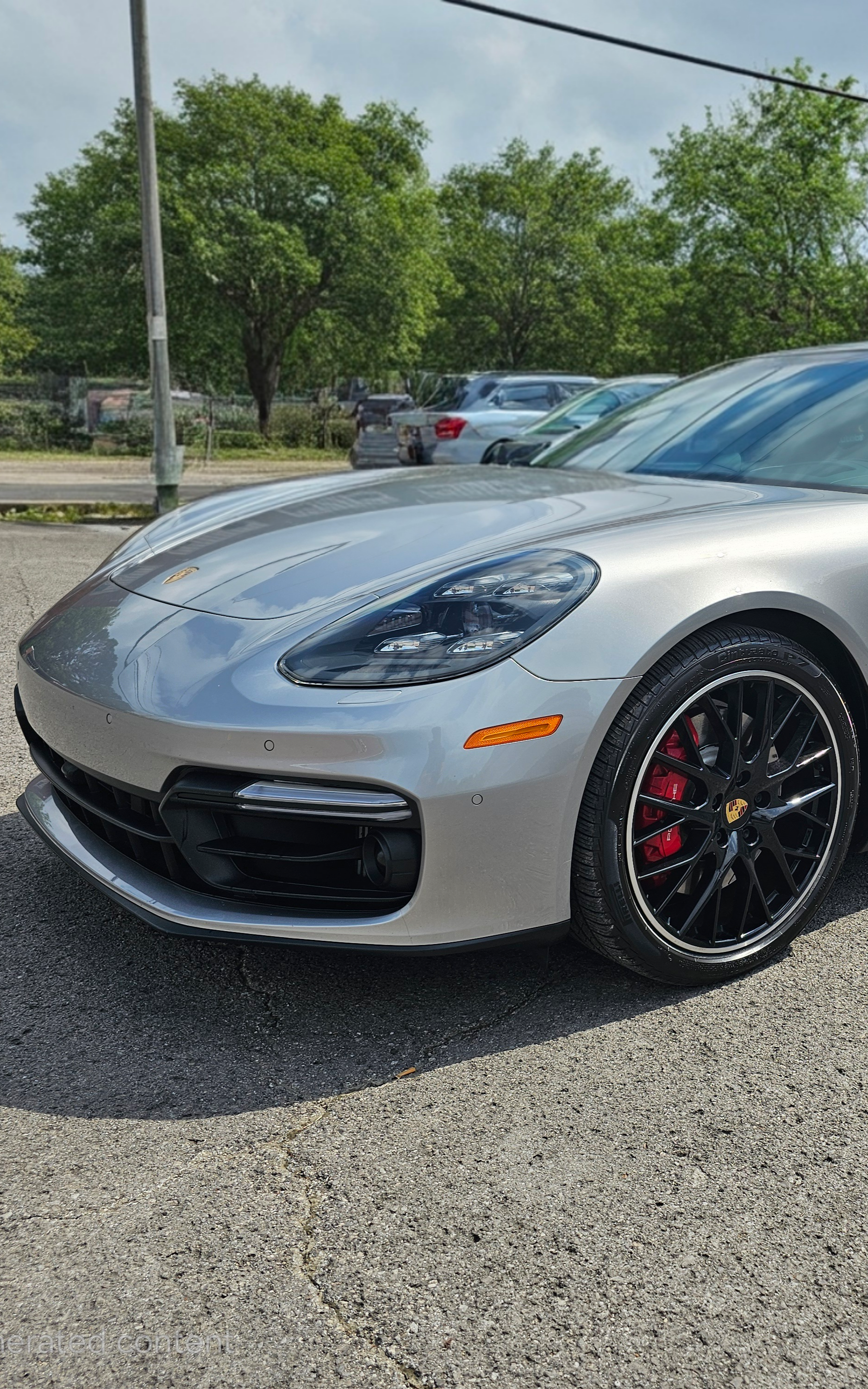 Silver Porsche Panamera GTS parked on gravel, near a building with a red awning.