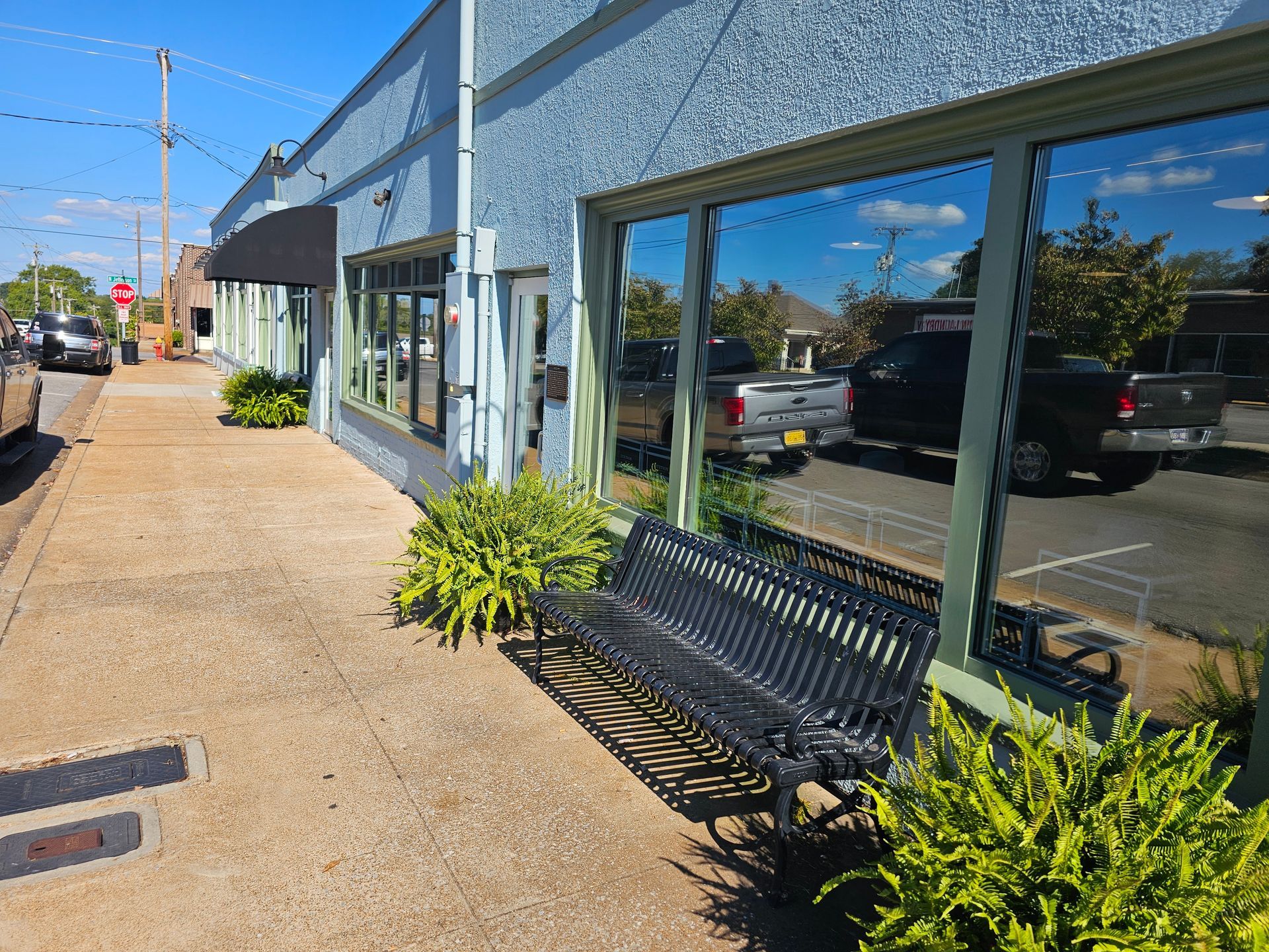A bench is sitting on the sidewalk in front of a building.