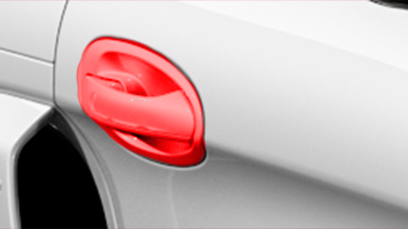 A close up of a white car with a red door handle.