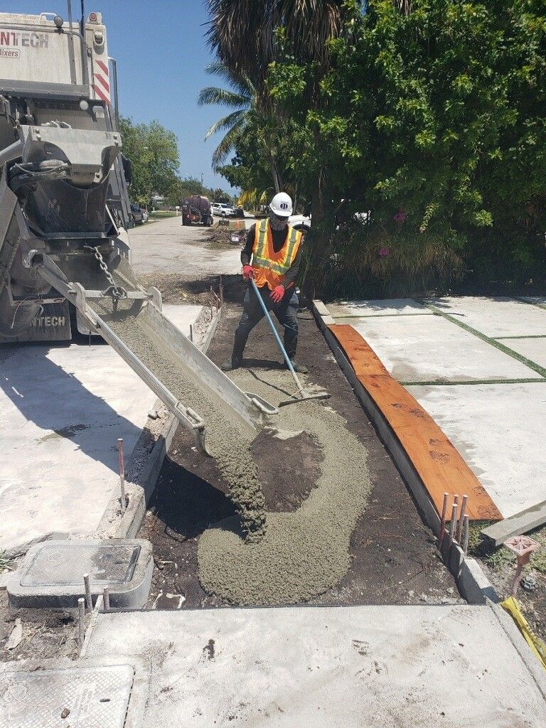 A construction worker is pouring concrete on a sidewalk.