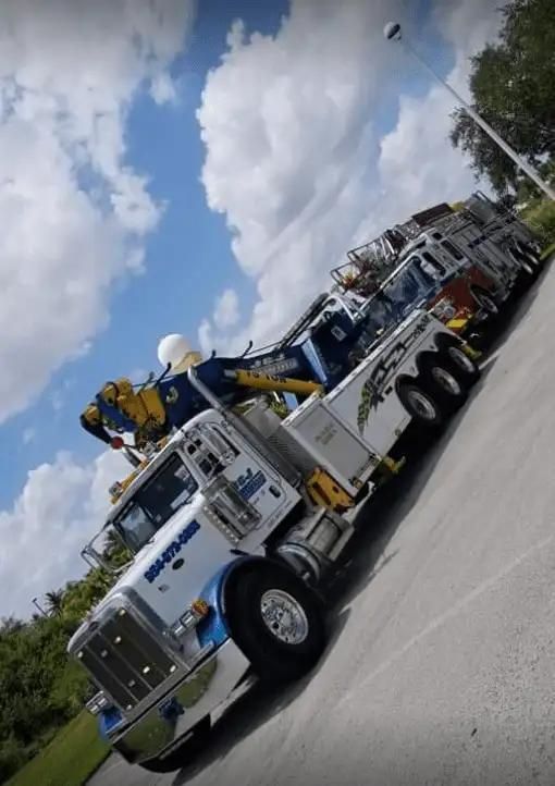 White and blue utility truck with equipment parked on a road under cloudy sky