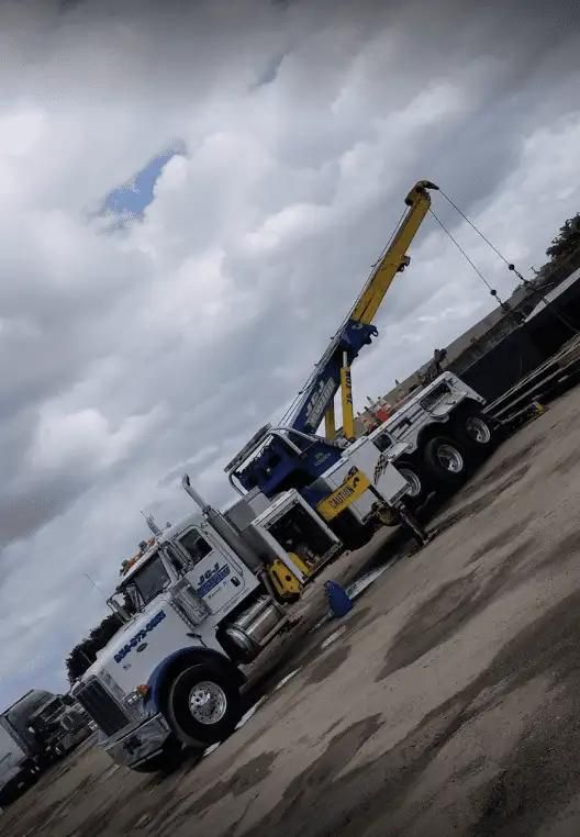 White crane truck parked on a slanted lot under a cloudy sky