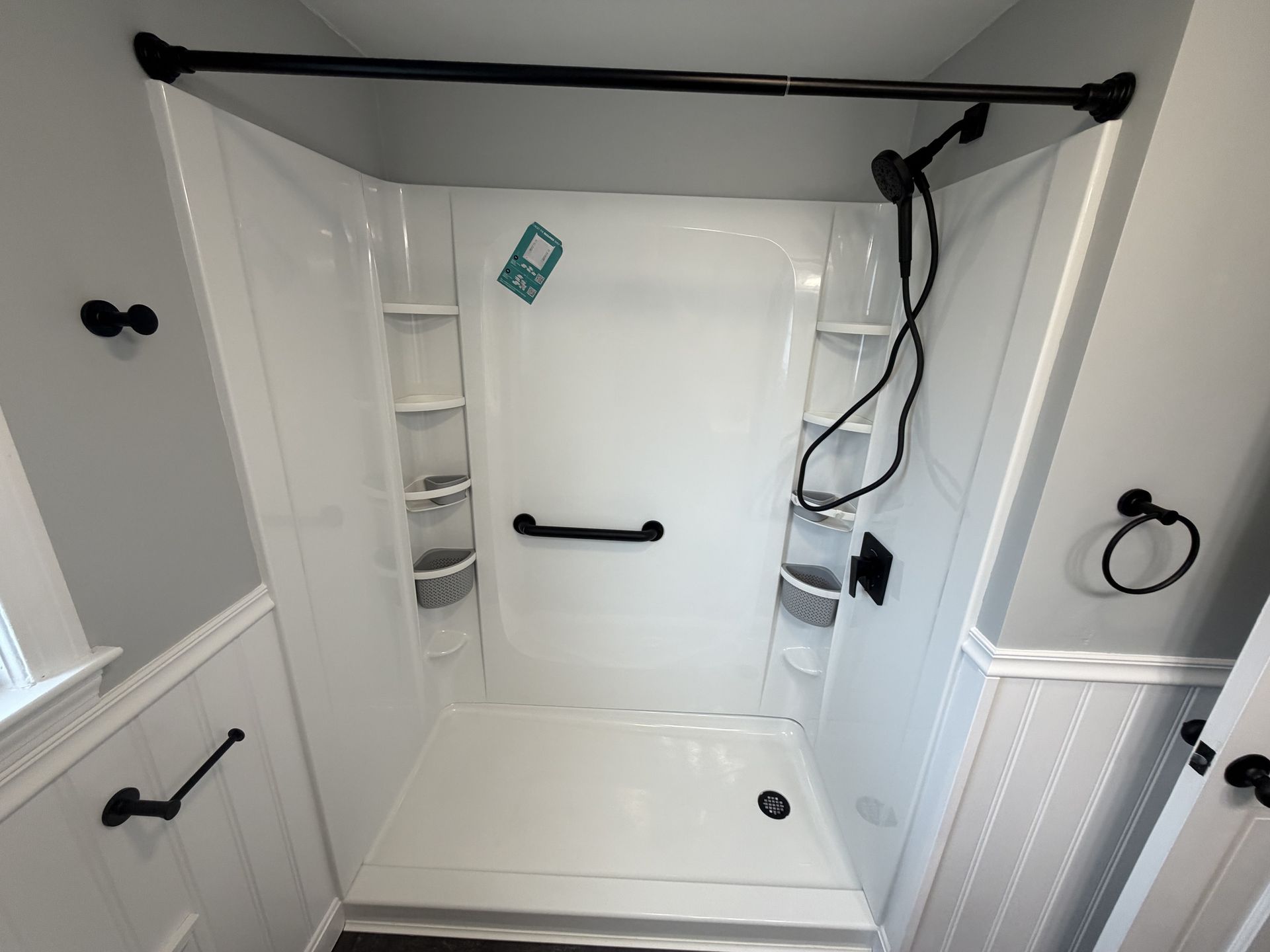 White walk-in shower with built-in shelves, grab bars, and a bench seat in a tiled bathroom