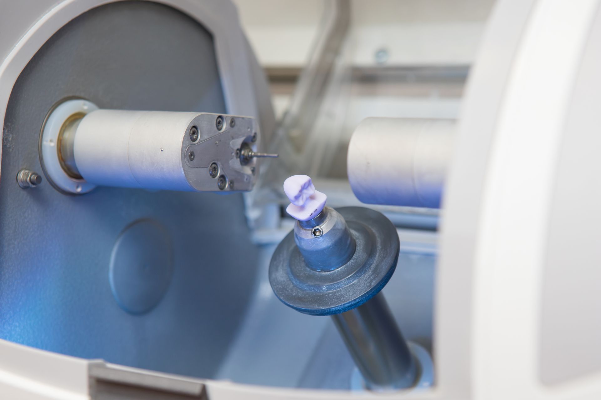 CAD/CAM milling machine shaping a dental crown restoration. CAD/CAM milling machine shaping a dental crown restoration.