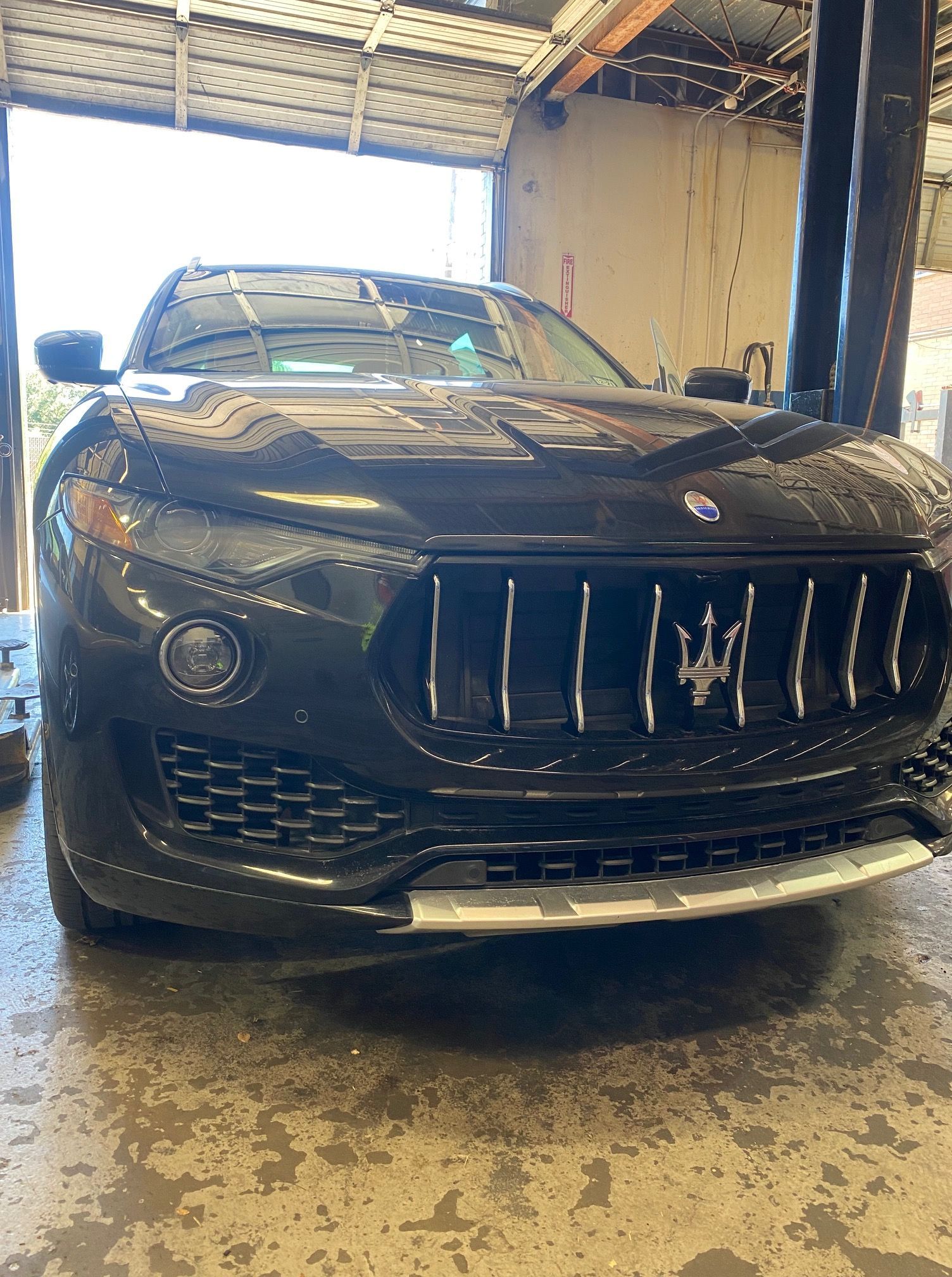 Black Maserati SUV parked inside a garage, with the front facing the viewer | Proline Auto.