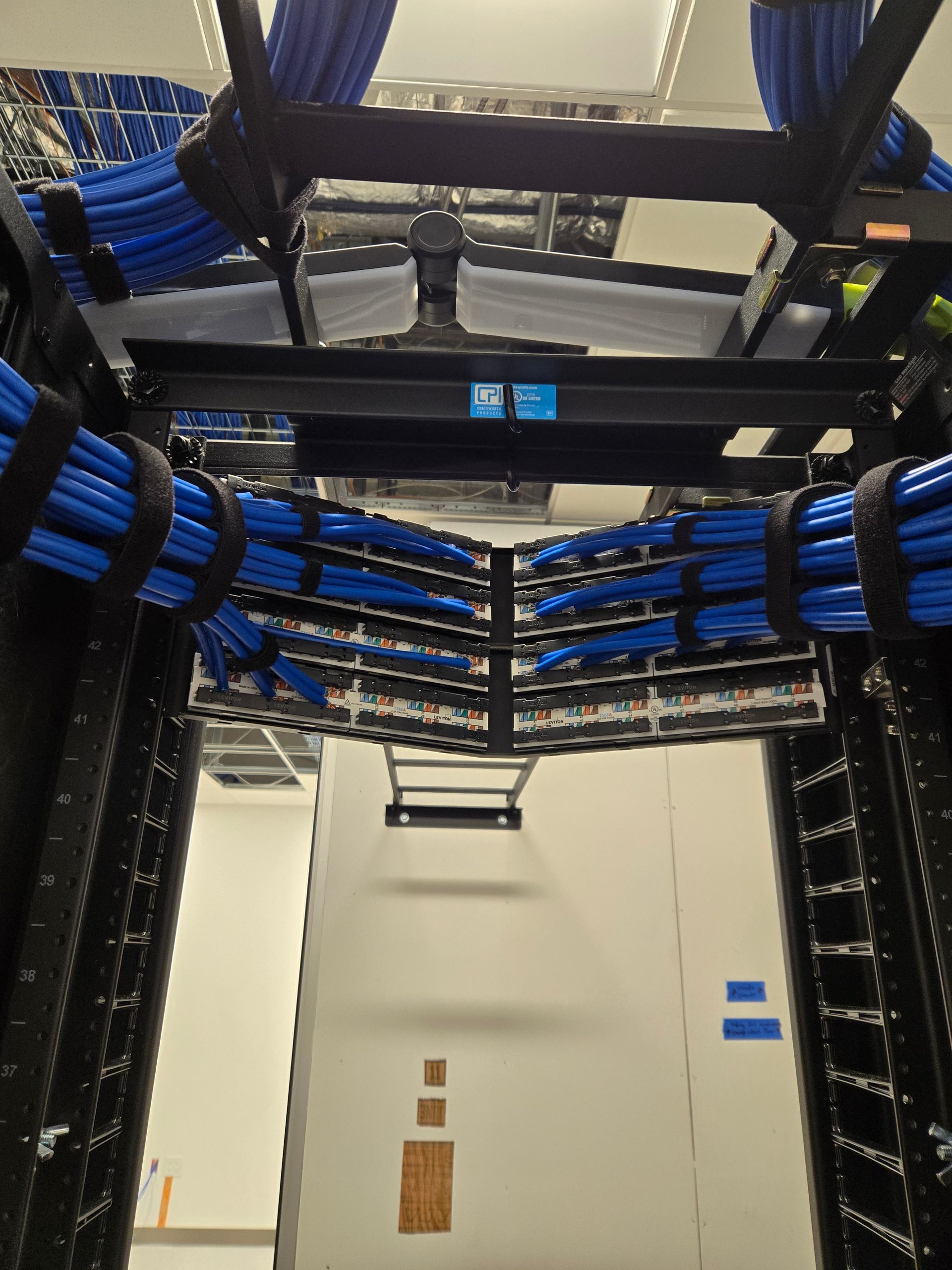 Blue network cables organized in a server rack, cables secured with Velcro straps.