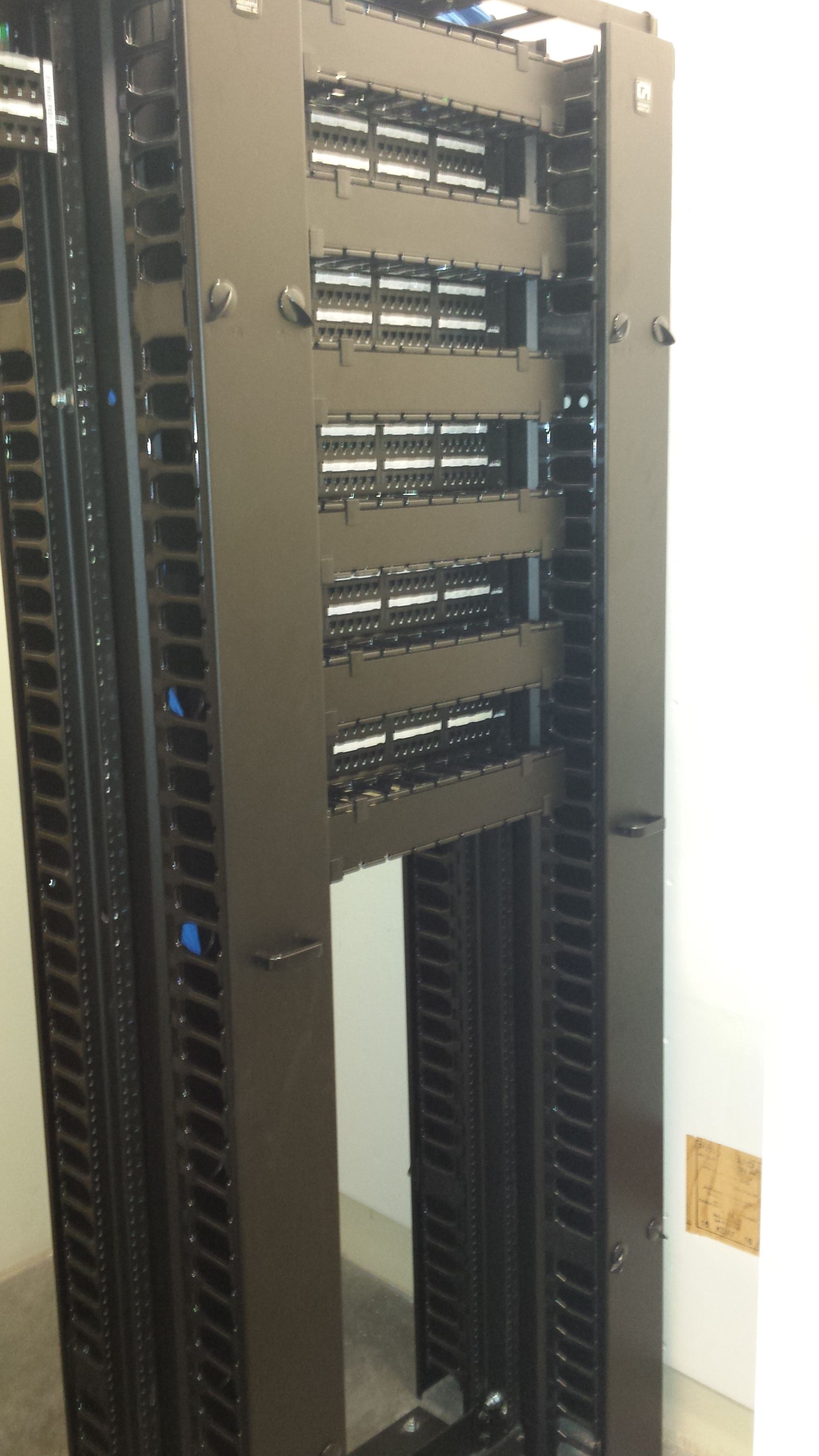 Black server rack, partially filled, with patch panels and cable management.