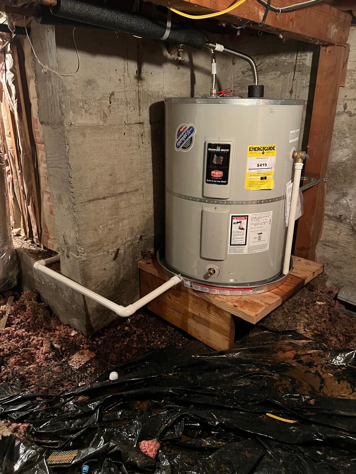 Water heater in a basement setting. The unit sits on a wooden platform with plumbing visible.