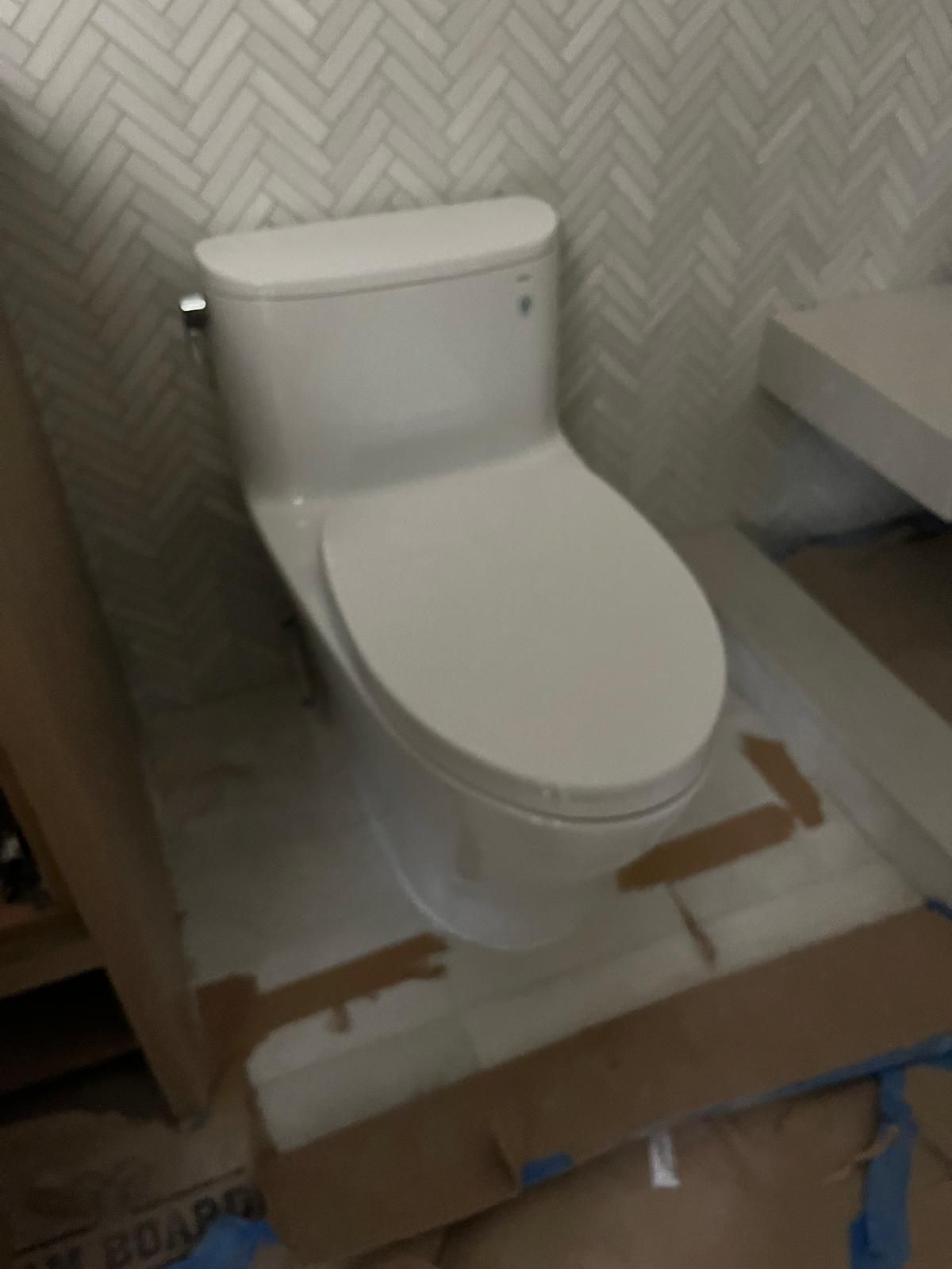 White toilet in a bathroom with herringbone patterned tile.