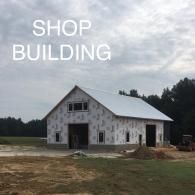 White shop building with a metal roof on a dirt lot under a cloudy sky