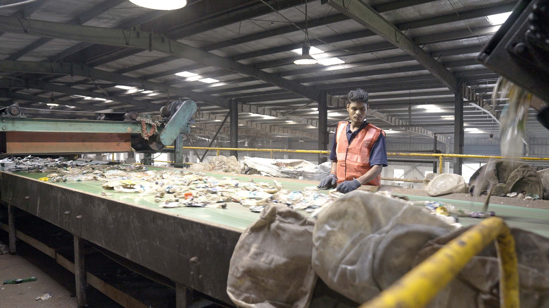 A conveyor belt filled with shredded plastic is in a warehouse.