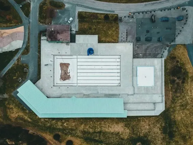 Aerial view of a large flat commercial roof with rooftop structures and surrounding industrial property.
