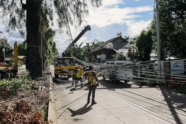 Utility workers repairing fallen power lines and storm damage on a residential street