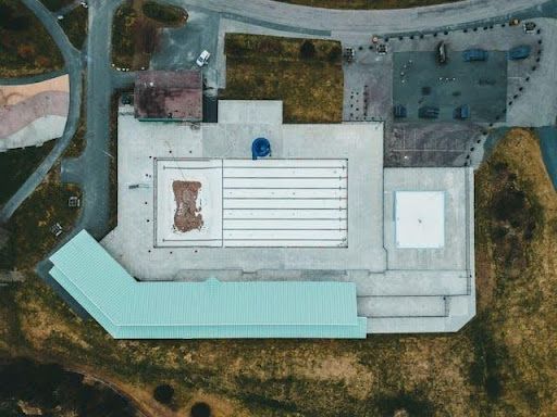 Aerial view of a large flat commercial roof with rooftop structures and surrounding industrial property.