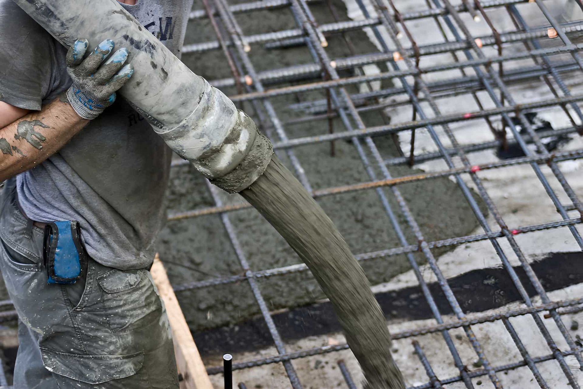 A Man Is Pouring Concrete Into A Steel Structure — JGA Concreting Pty Ltd In Berrimah, NT