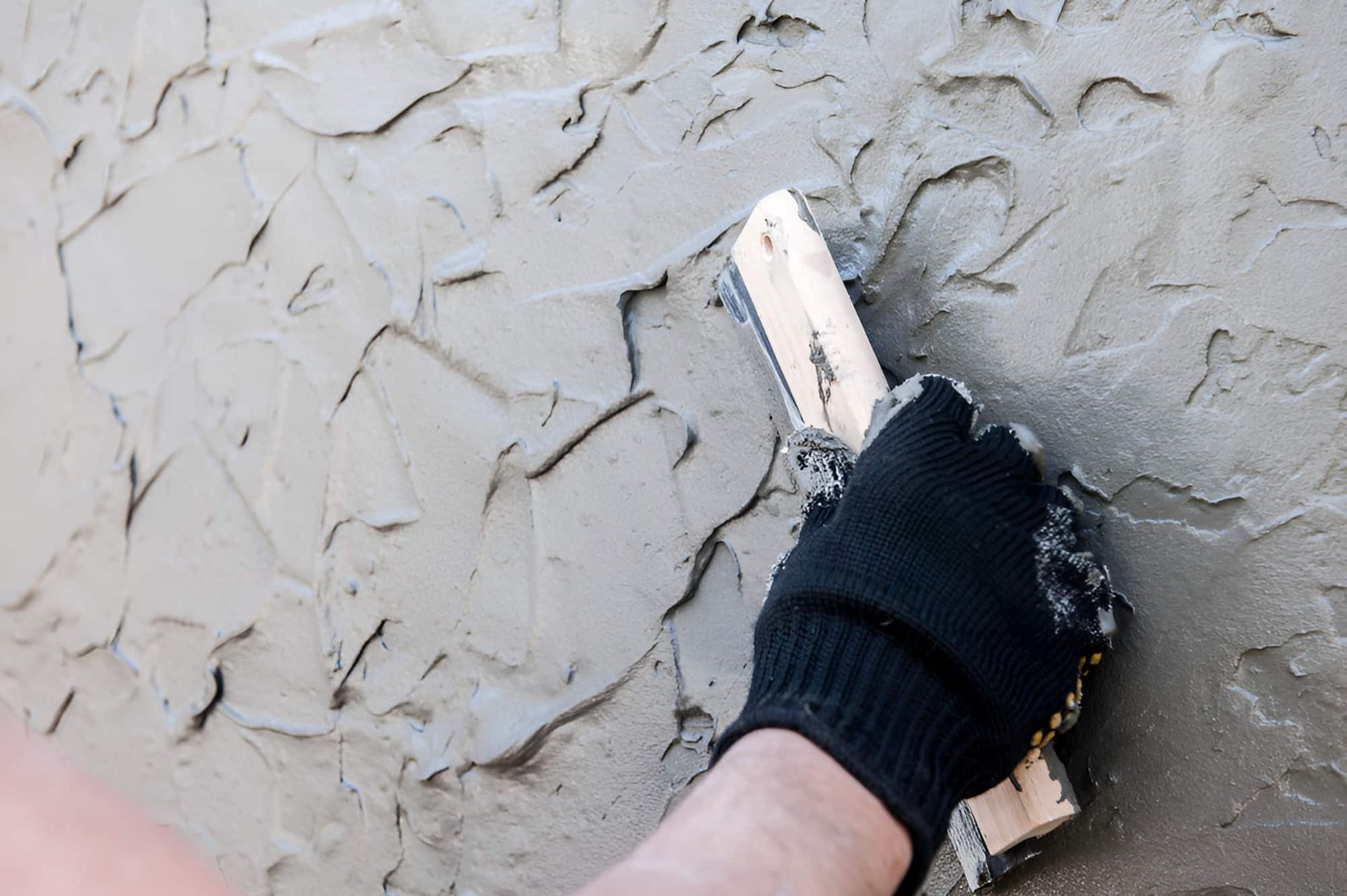 A Person Is Plastering A Wall With A Trowel — JGA Concreting Pty Ltd In Berrimah, NT
