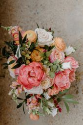 A vibrant floral bouquet featuring pink peonies, soft orange ranunculus, white roses.