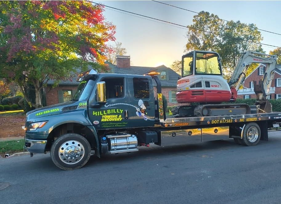 White flatbed tow truck with a forklift on the back, parked outdoors under a blue sky.