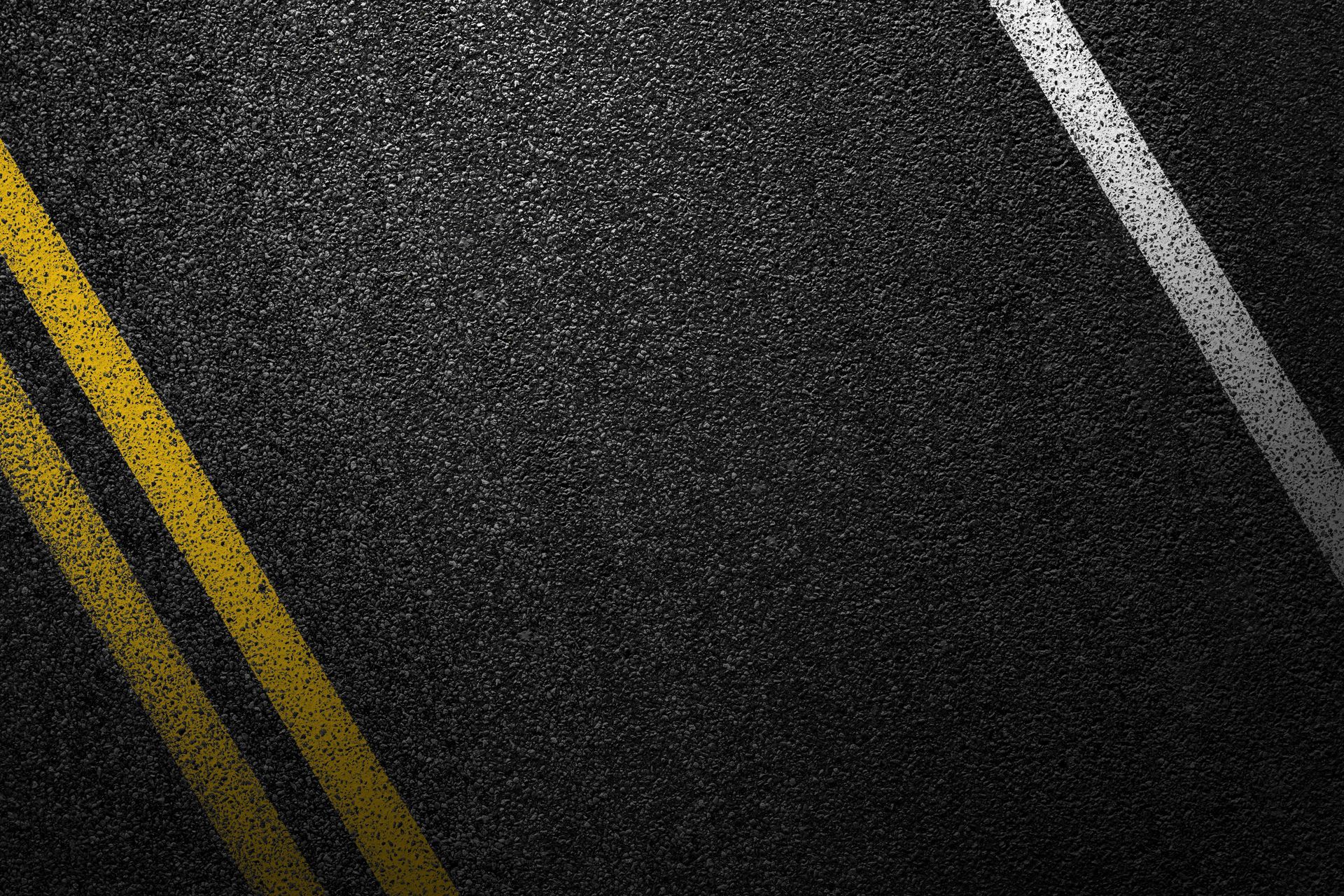 Dark asphalt road with double yellow center lines and a white edge line.