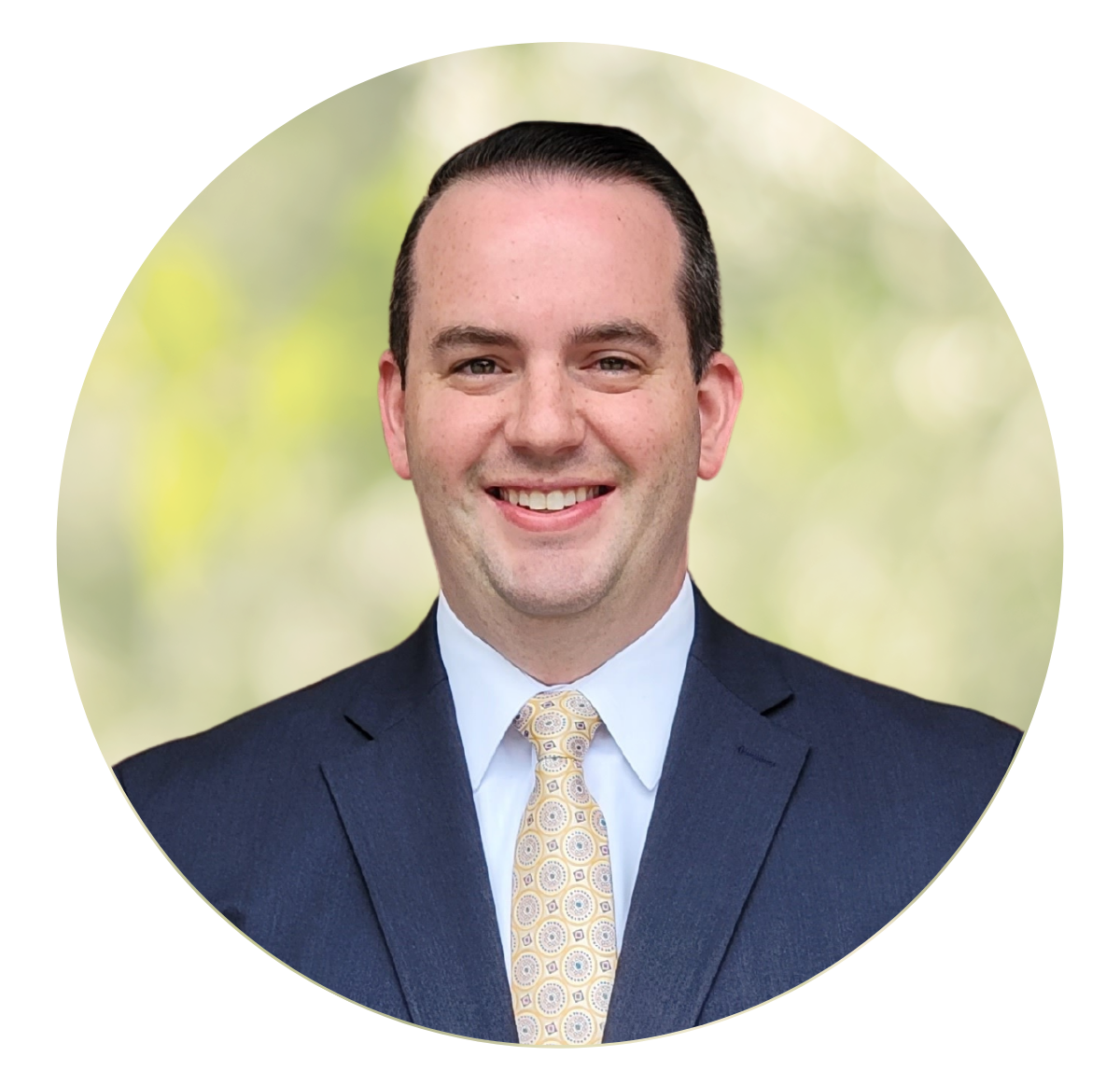 Smiling man in a navy suit and gold tie against a soft green background
