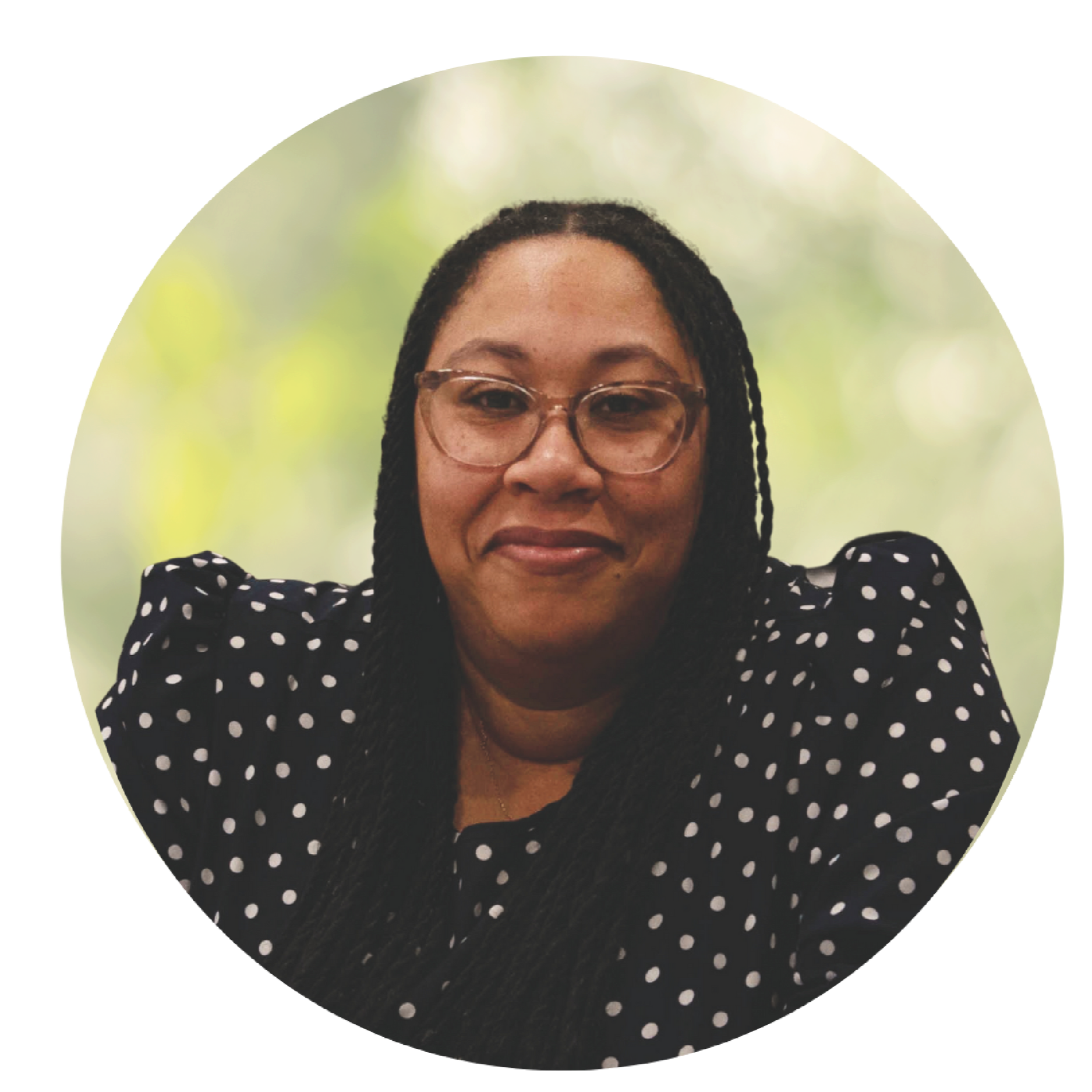 Smiling woman with glasses in a black polka-dot blouse against a soft green background