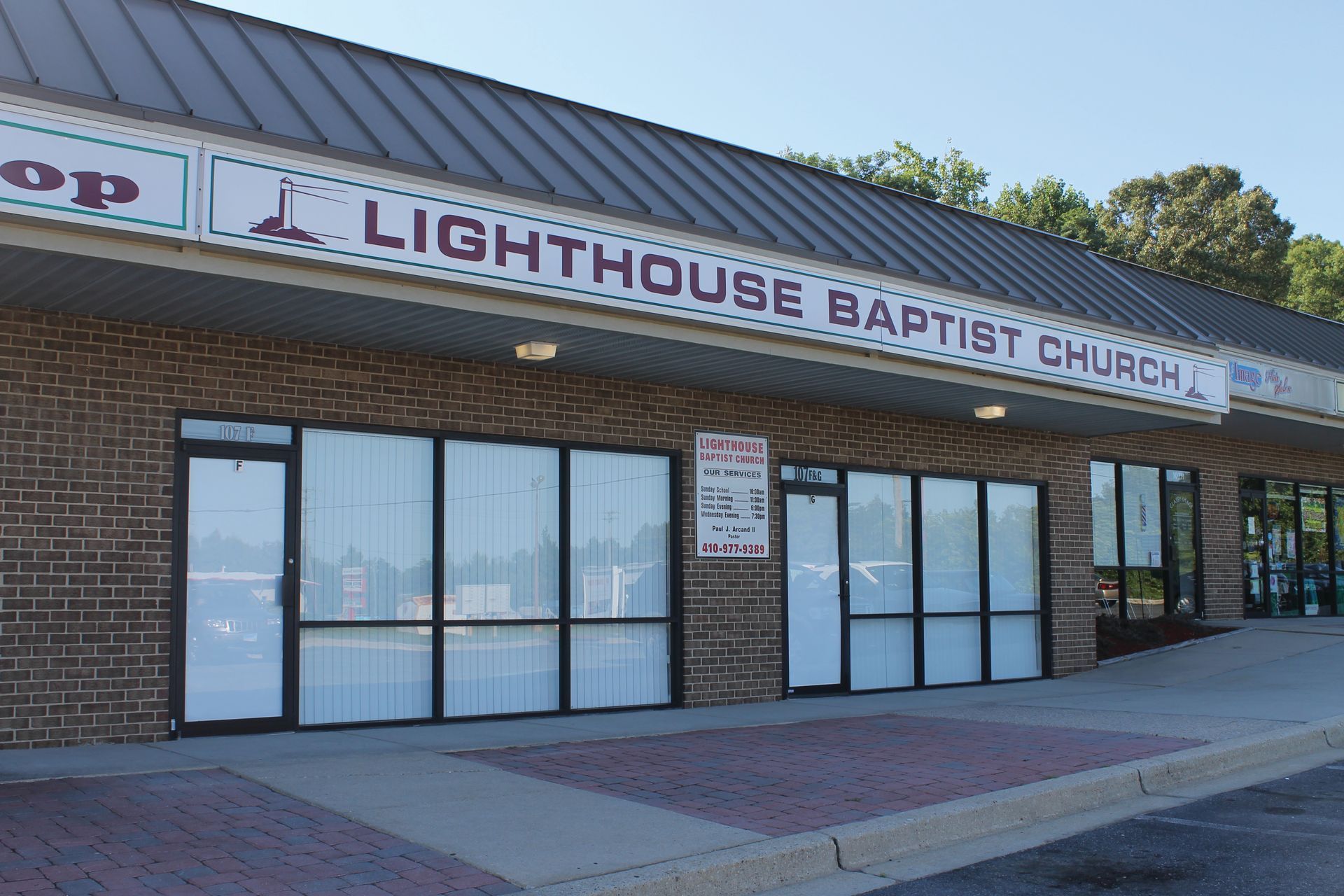 Exterior of Lighthouse Baptist Church storefront with brick facade and glass doors under a metal roof