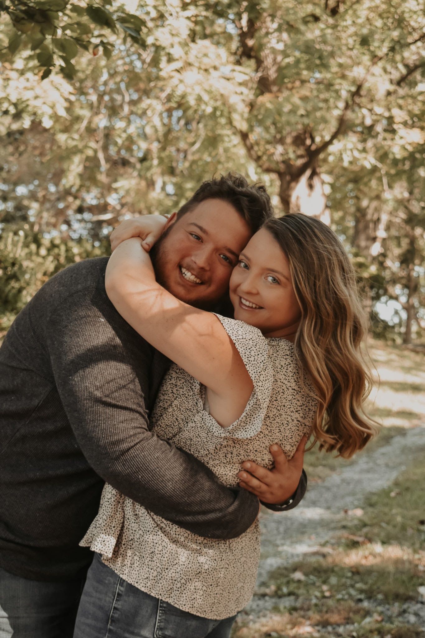 Smiling couple hugging outdoors under flowering trees
